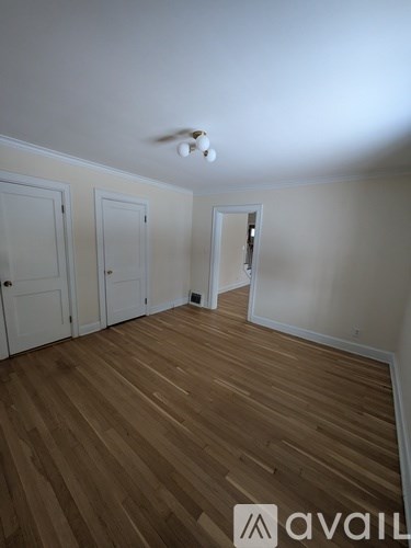 A room with wooden floors and three doors.