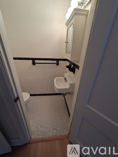 A bathroom with a toilet, sink, and a cabinet.