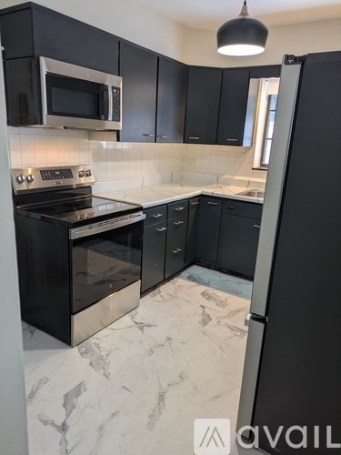 A kitchen with black cabinets and a marble floor.