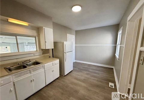 A kitchen with white cabinets and a grey wall.