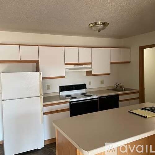 A kitchen with white appliances and wooden cabinets.