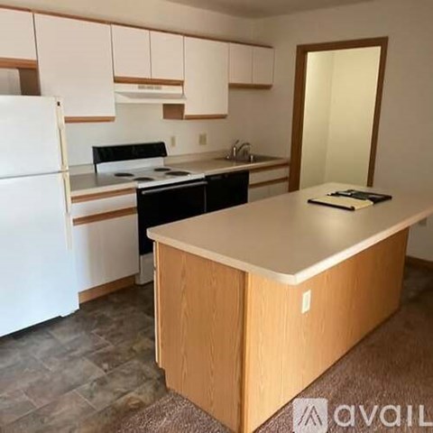 A kitchen with a white fridge, black stove and wooden island.
