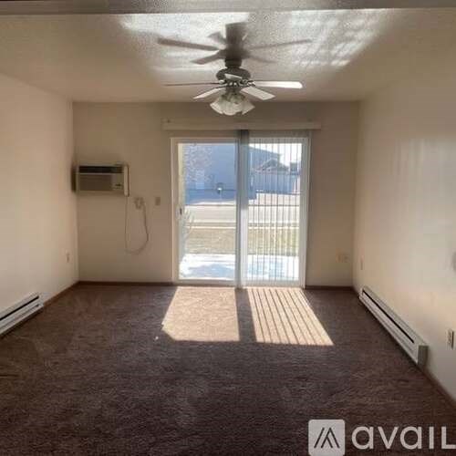 A room with a ceiling fan and a window with blinds.