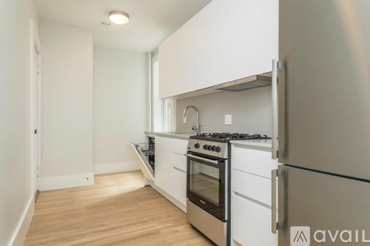 A kitchen with white cabinets and a stainless steel refrigerator.