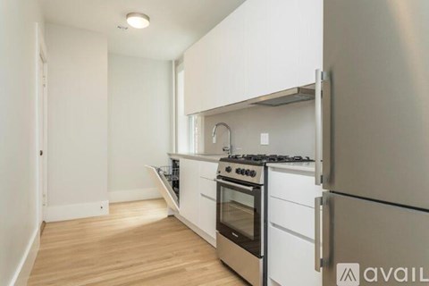 A kitchen with white cabinets and a stainless steel refrigerator.