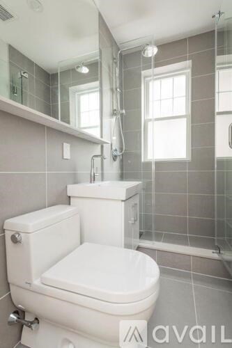 A white toilet in a tiled bathroom with a window.