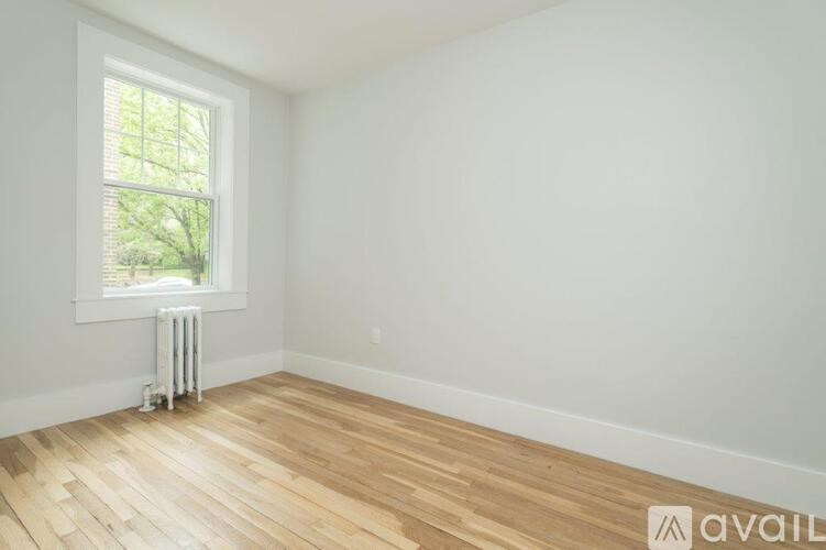 A room with wooden flooring and a window with blinds.