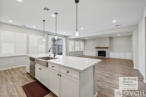 A kitchen with white cabinets and a wooden floor.