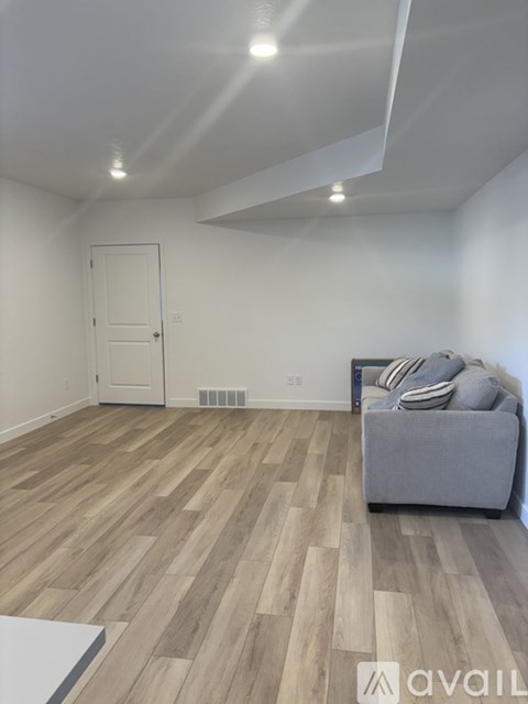 A living room with a grey couch and wooden flooring.