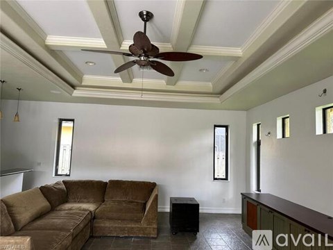 A living room with a brown couch and a ceiling fan.