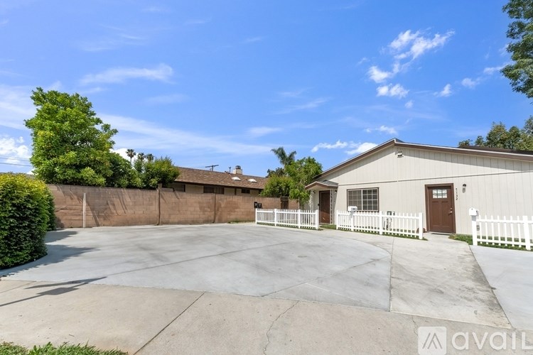 A large, empty parking lot in front of a two-story building with a white picket fence.