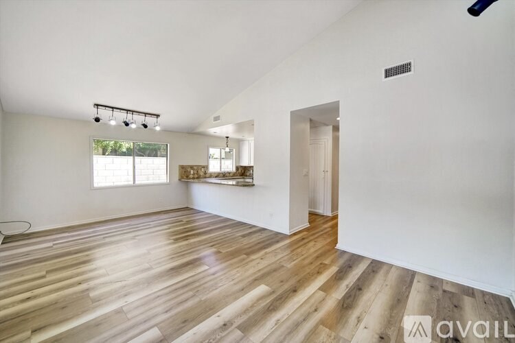 A room with wooden flooring and a window with a view of trees.