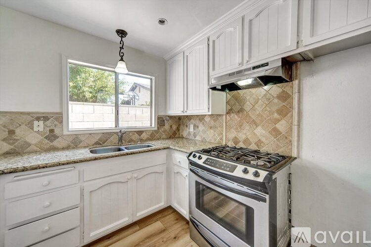 A kitchen with a stove, sink, and cabinets.