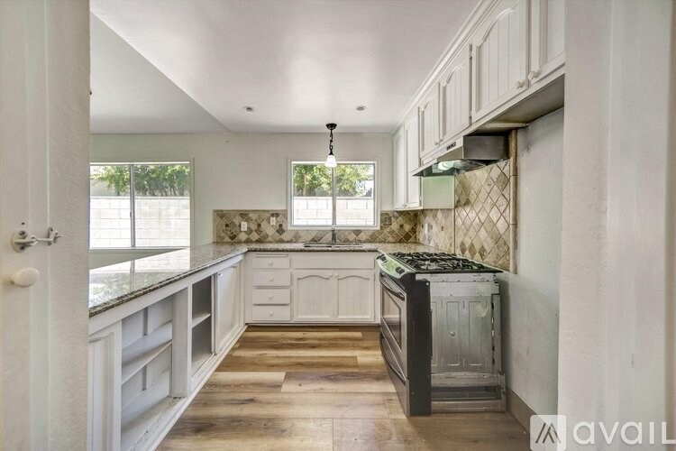 A kitchen with white cabinets and a black stove top oven.