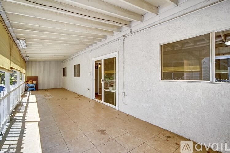A spacious room with a tiled floor and a balcony on the left side.