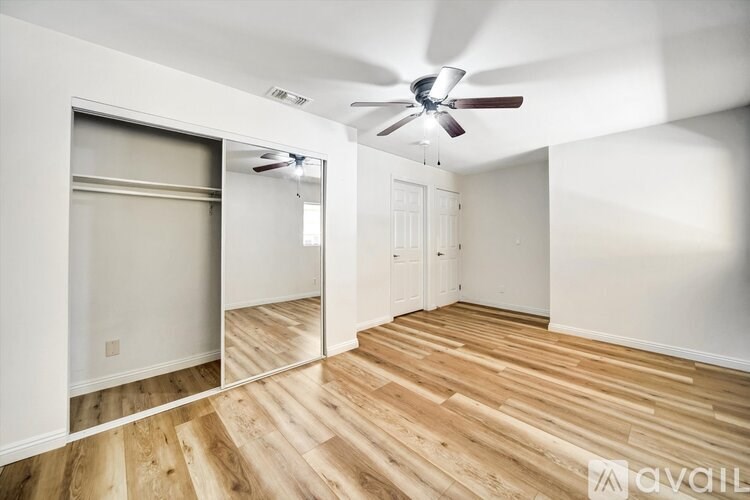 A room with a ceiling fan and wooden flooring.