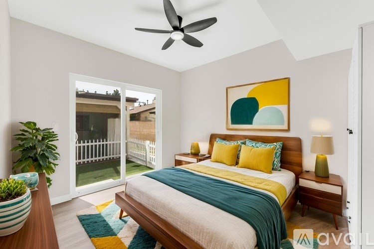 A bedroom with a bed, a ceiling fan, and a painting on the wall.