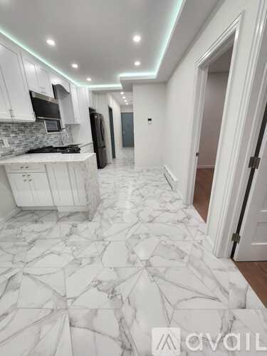 A kitchen with white cabinets and a marble floor.