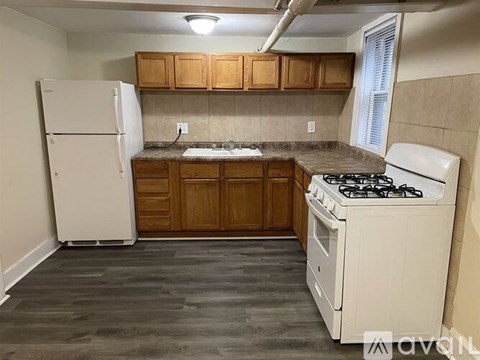 A kitchen with a white refrigerator, white stove, and wooden cabinets.