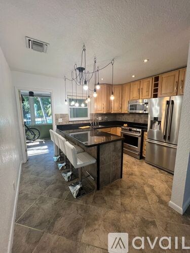 A kitchen with a large island in the middle and a dining table with chairs.