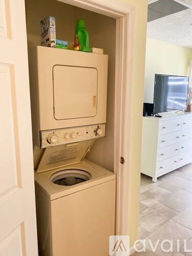 A white washing machine is in a small open cabinet.