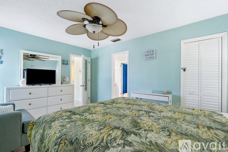 A bedroom with a bed, dresser, and ceiling fan.