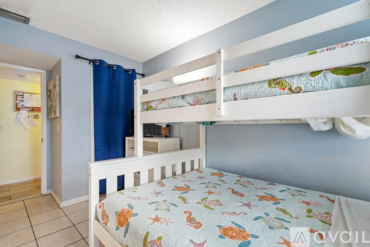 A room with a bunk bed and a blue curtain.