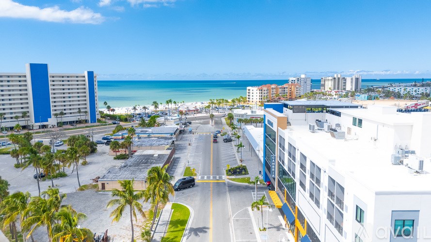 A view of a beachfront area with buildings, palm trees, and a clear sky.