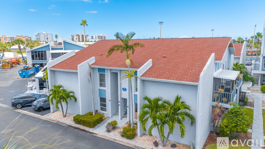 A white building with a red roof is surrounded by palm trees.