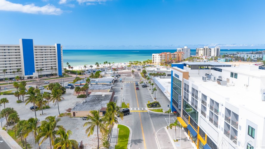 A view of a beachfront street with buildings on either side and palm trees in the foreground.