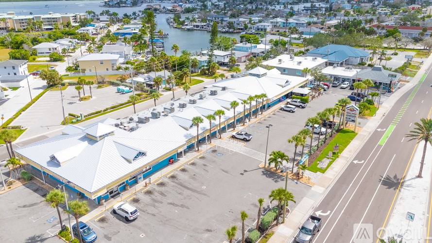 A parking lot with a building and palm trees.