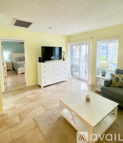 A living room with a white coffee table and a flat screen TV on a white cabinet.