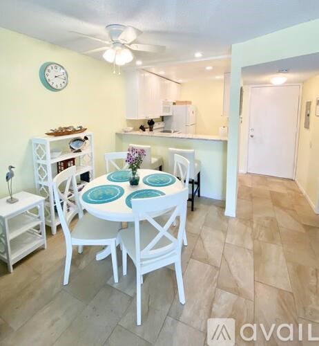 A dining room with a table set for four and a clock on the wall.