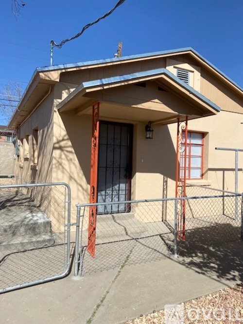 A house with a brown roof and a red gate.