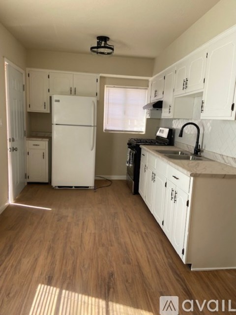 A kitchen with white appliances and wooden floors.