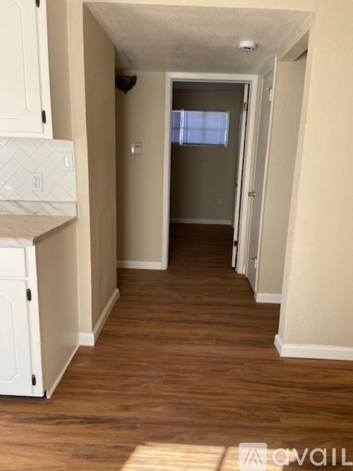 A long hallway with wood floors and white walls.