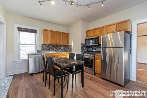 A kitchen with a table and chairs in front of a stove and refrigerator.