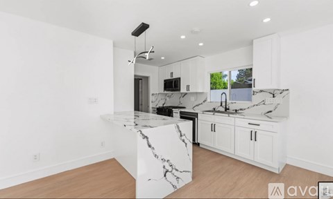 A modern kitchen with white cabinets and marble countertops.
