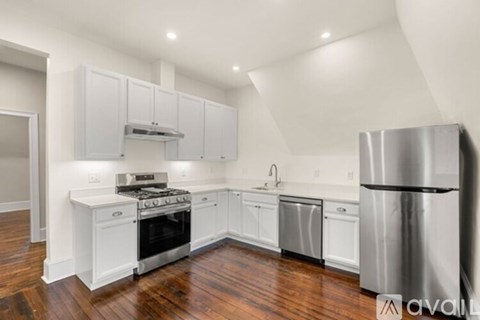 A kitchen with white cabinets and a stainless steel refrigerator.