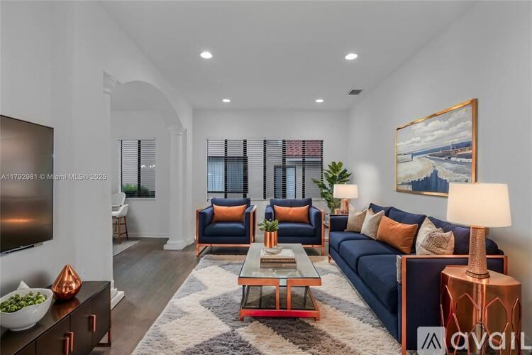 A living room with a dark blue sofa, a wooden coffee table, and a painting on the wall.