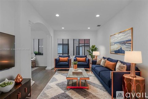 A living room with a dark blue sofa, a wooden coffee table, and a painting on the wall.