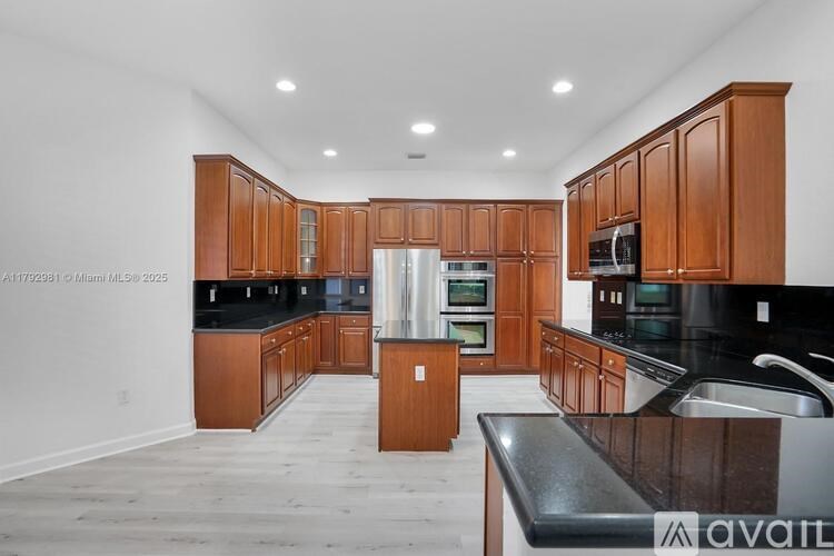 A kitchen with wooden cabinets and black countertops is available for rent.