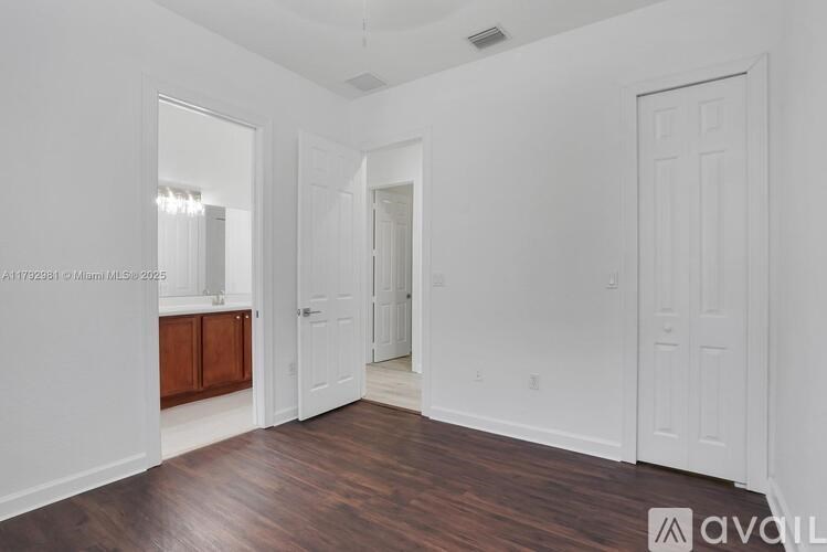 A spacious room with white walls and wooden flooring.
