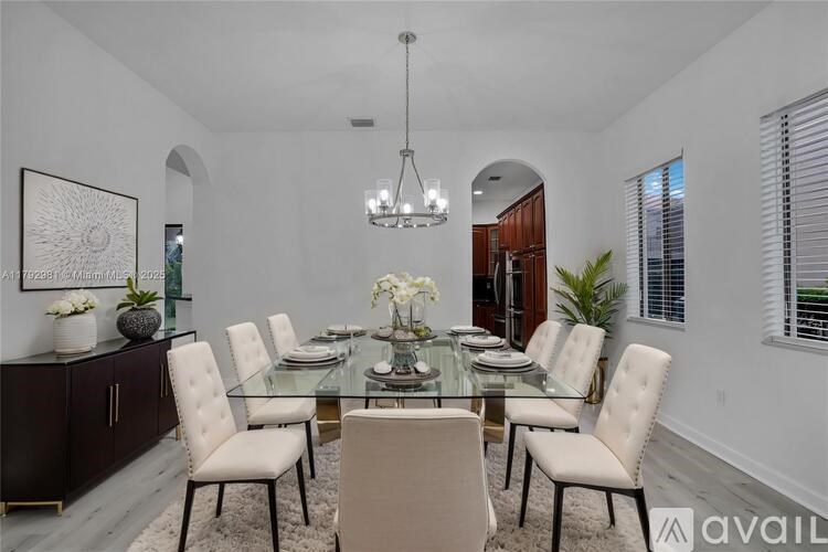A dining room with a glass table and white chairs.