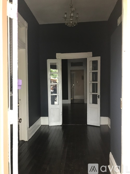A hallway with a chandelier and a white door.