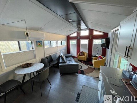 A living room with a grey couch, a yellow chair, and a round table with chairs around it.