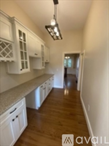 A kitchen with white cabinets and a wooden floor.