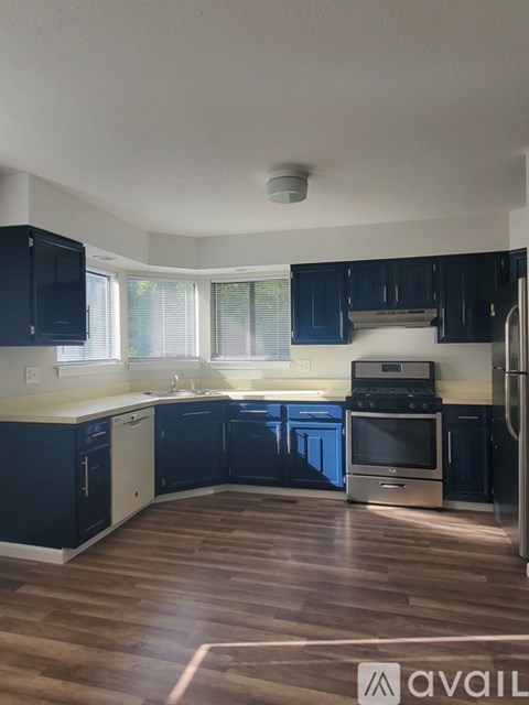 A kitchen with dark blue cabinets and wooden floors.
