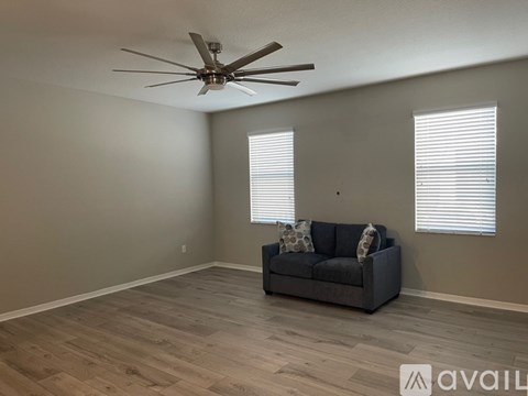 A living room with a grey couch and a ceiling fan.