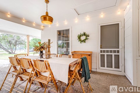 A dining room with a table set for six and a wreath on the wall.